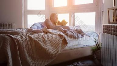 美丽浪漫的黑发女人躺在窗边与她可爱的缅因州考恩猫在惊人的日落。 慢慢慢慢